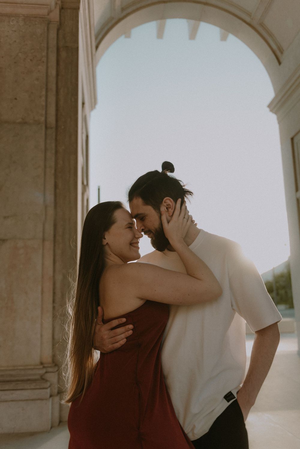 A romantic embrace captured under a grand stone archway.
