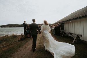 Wedding guests dance and celebrate on a scenic outdoor deck at sunset.