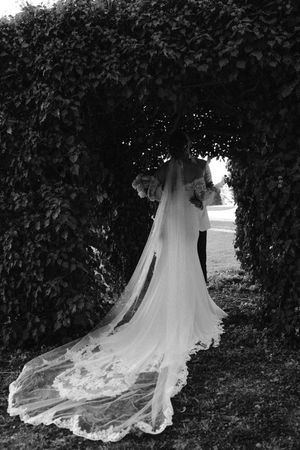 Elegant white wedding dress train photographed against lush ivy backdrop.