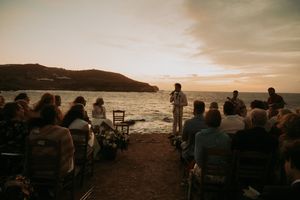 Coastal wedding ceremony setup with dramatic sunset and ocean backdrop.