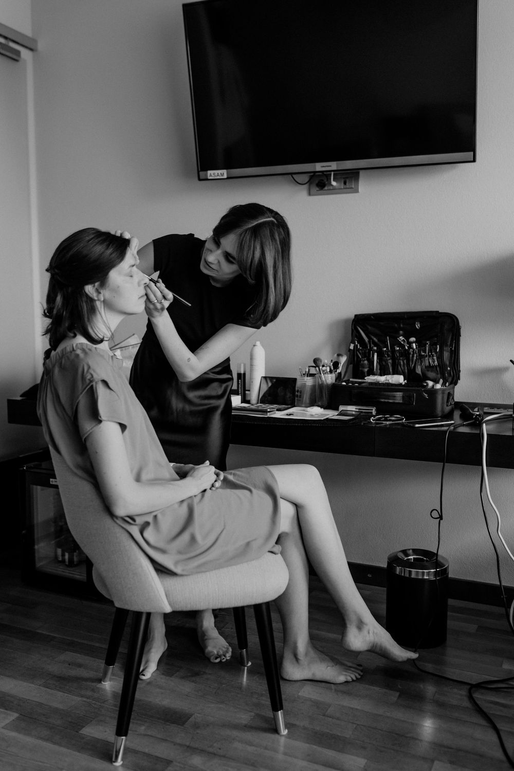 Getting ready scene with makeup application in a modern room with hardwood floors.