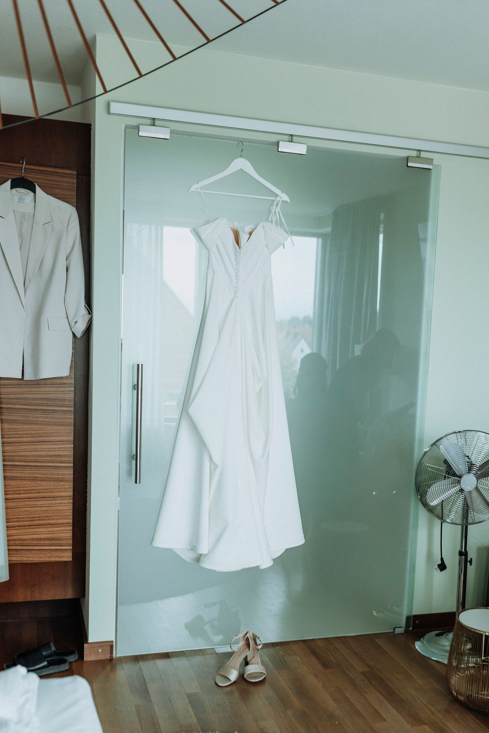 White shirts hanging in a minimalist dressing room with wooden accents and natural light.