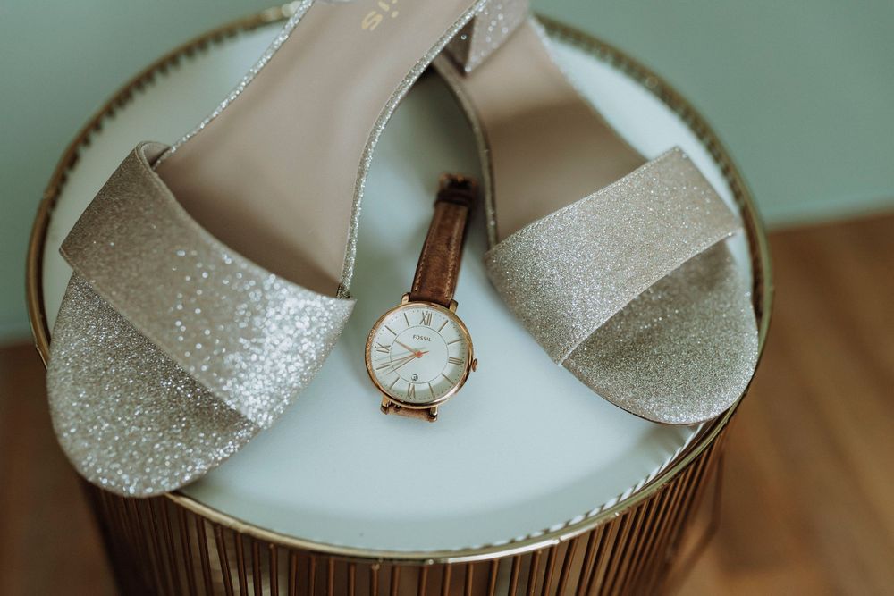 White cupcakes with glitter frosting displayed on a wooden surface with a watch.