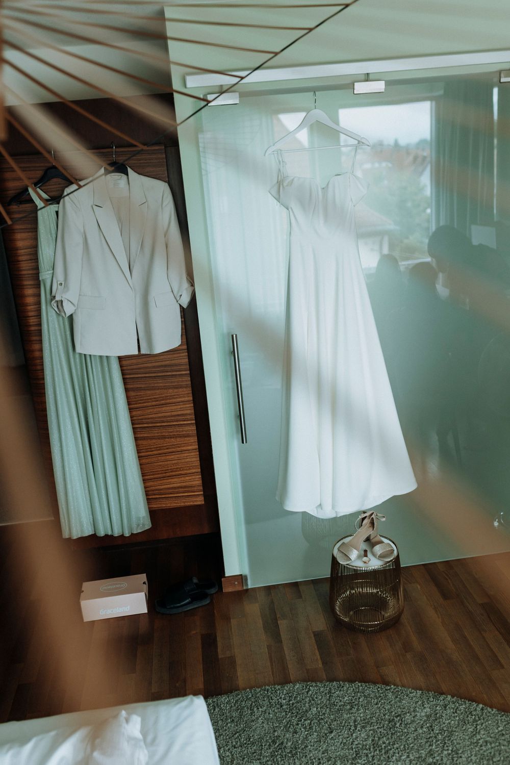 White wedding attire displayed in a modern dressing room with hardwood floors.