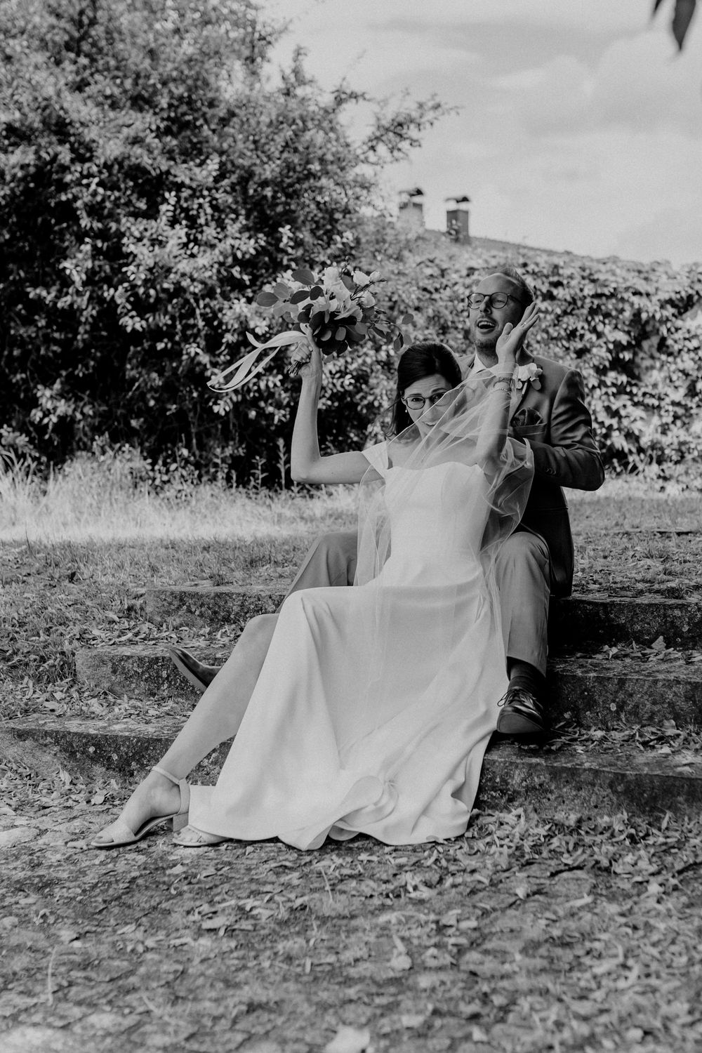 Romantic black and white photo of newlyweds sitting together outdoors.