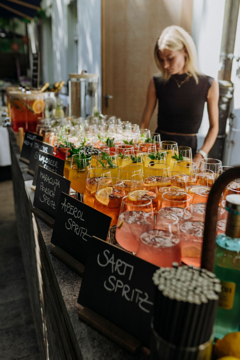 Colorful cocktails lined up on a bar with chalkboard drink labels.