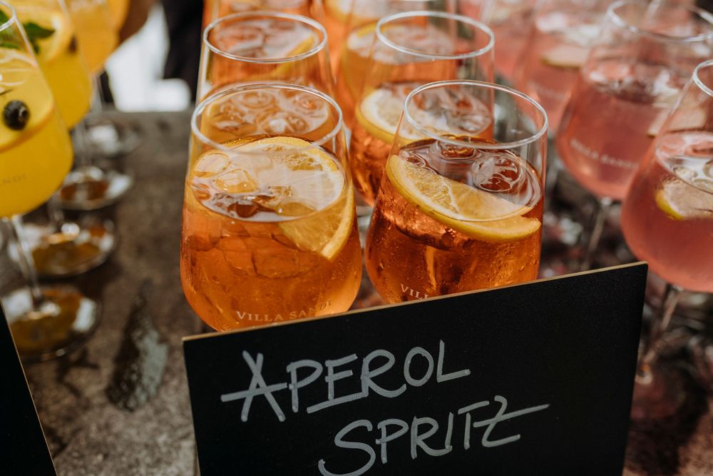 Orange Aperol Spritz cocktails lined up on a dark surface with garnishes.