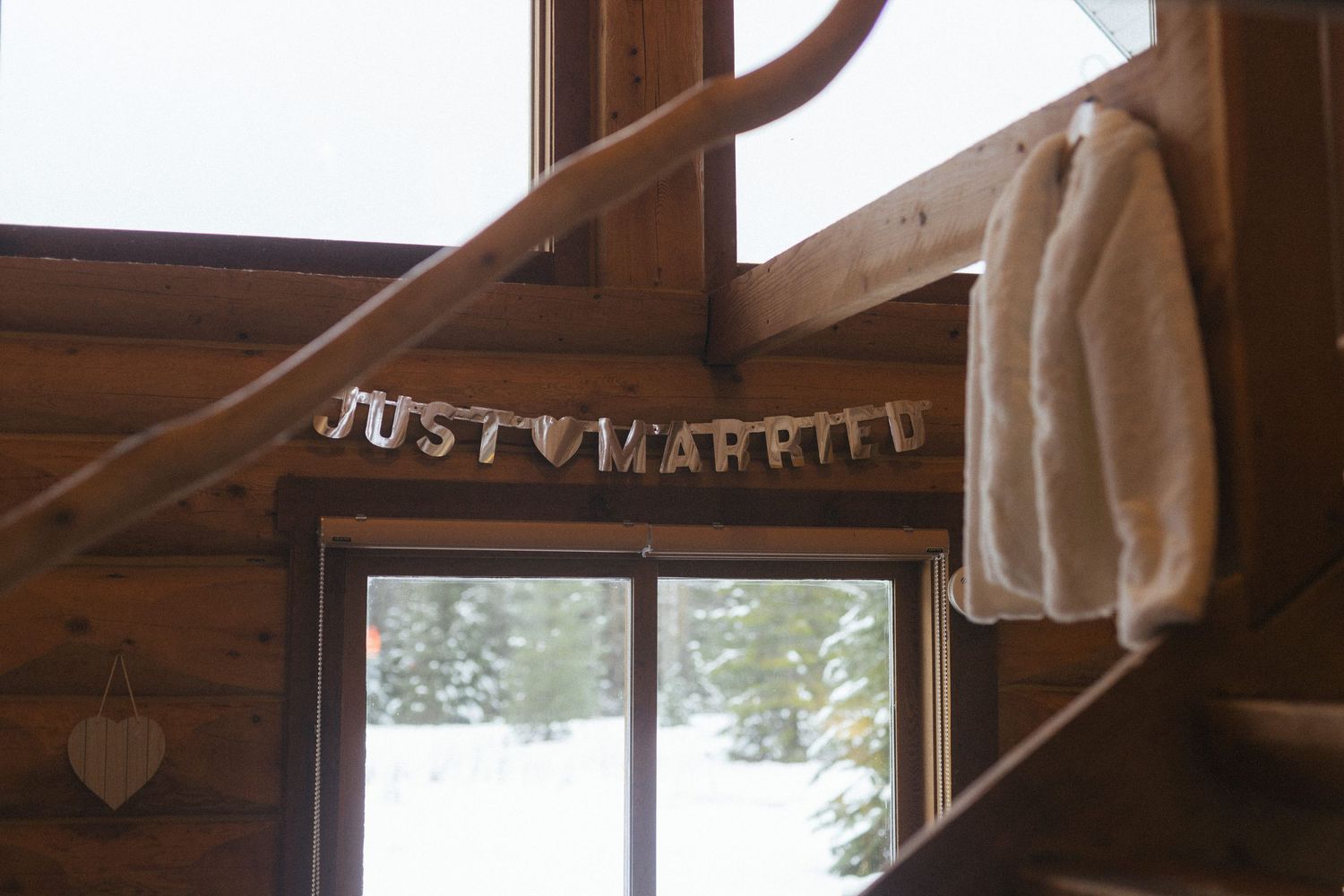 a "just married" sign hands in a log cabin alongside a white fur coat