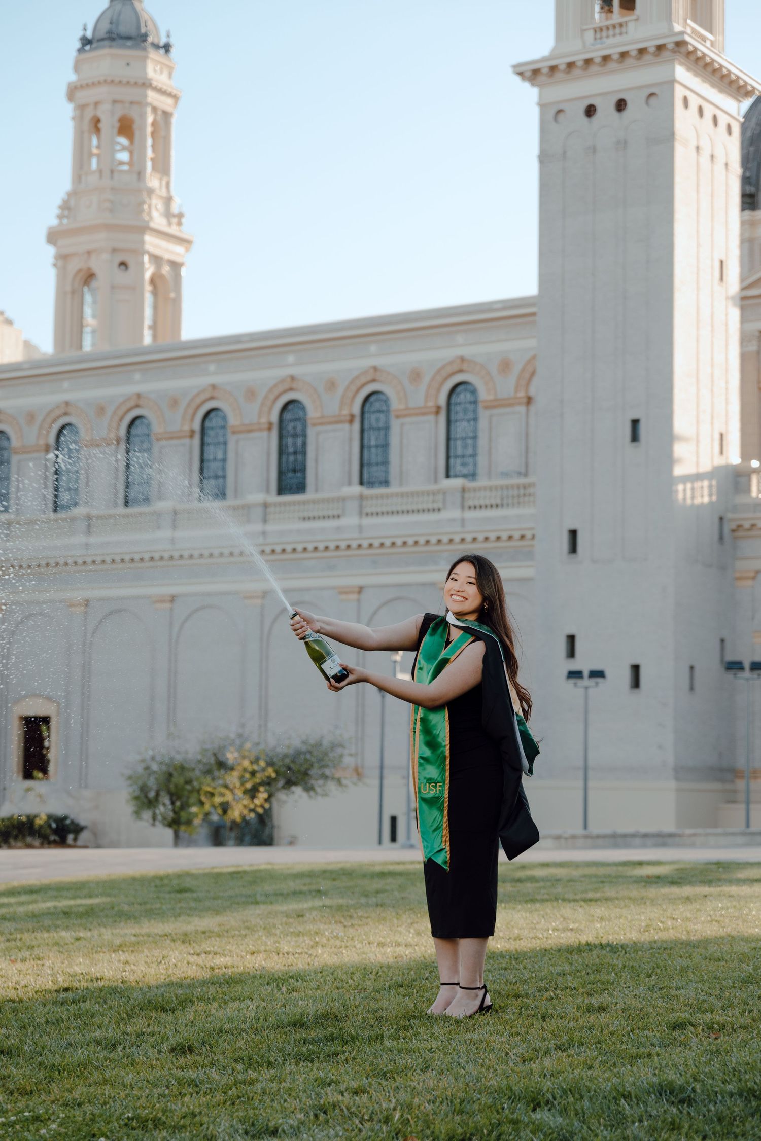 USF graduate pops and sprays champagne for her grad photoshoot. Grad photos taken by Bay Area Graduation Photographer.