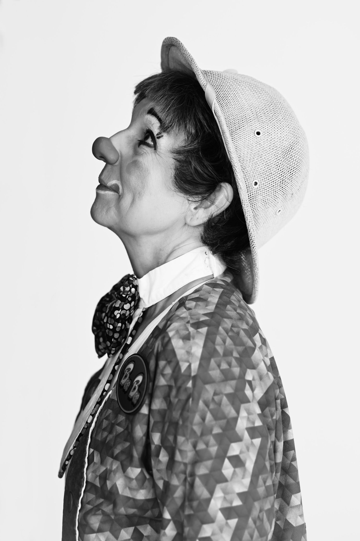Black and white clown profile portrait wearing a clown hat and patterned jacket.