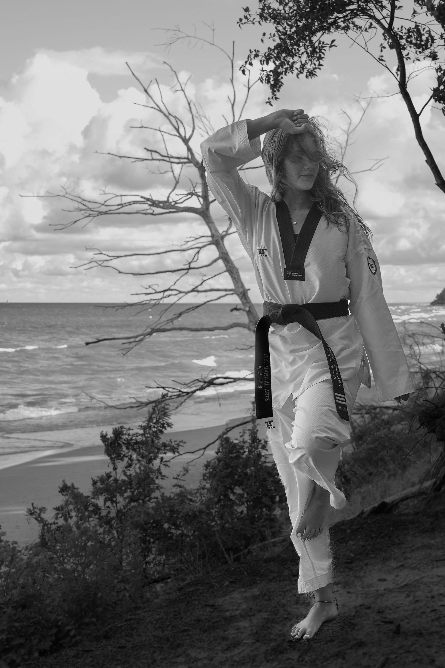 A sequence of black and white photos shows a person in white clothing dancing against a dramatic coastal landscape.