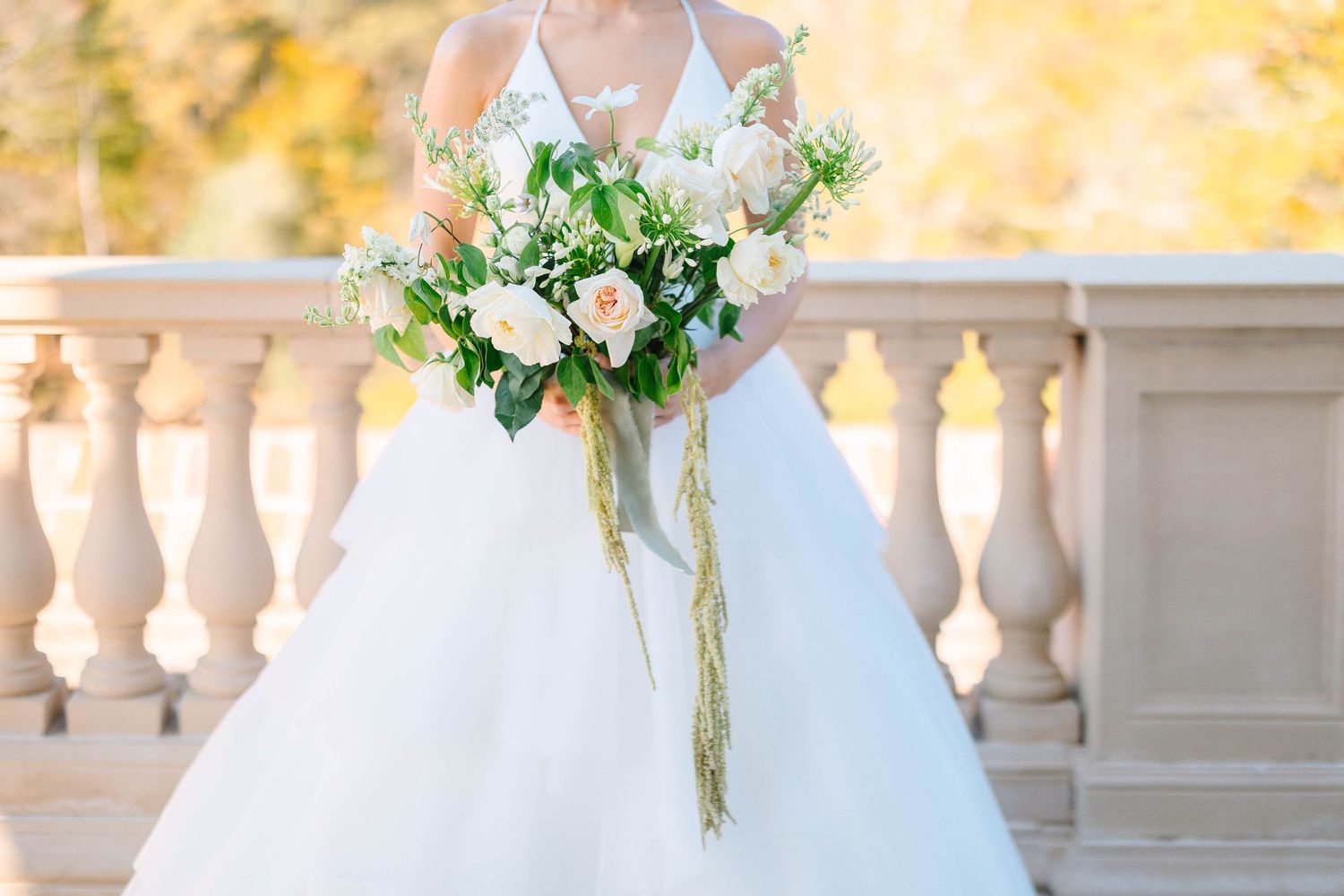 Elegant white bridal shoes with crystal embellishments and wedding rings displayed on a wooden surface.