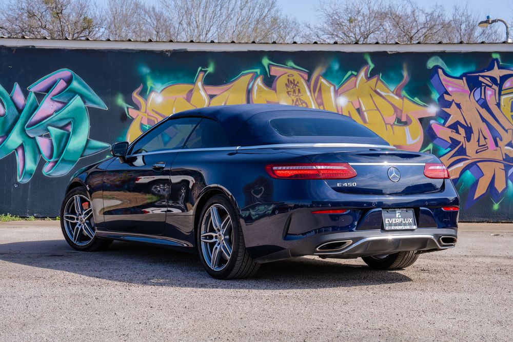 Black Mercedes-Benz S-Class coupe parked in front of colorful graffiti wall with stylized street art.