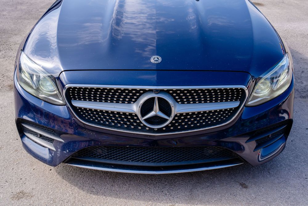 Close-up view of a deep blue Mercedes-Benz front grille with diamond pattern and prominent three-pointed star emblem.