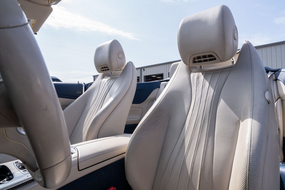 Luxurious cream leather interior of Mercedes-Benz S-Class showing front seats with detailed stitching and headrests.