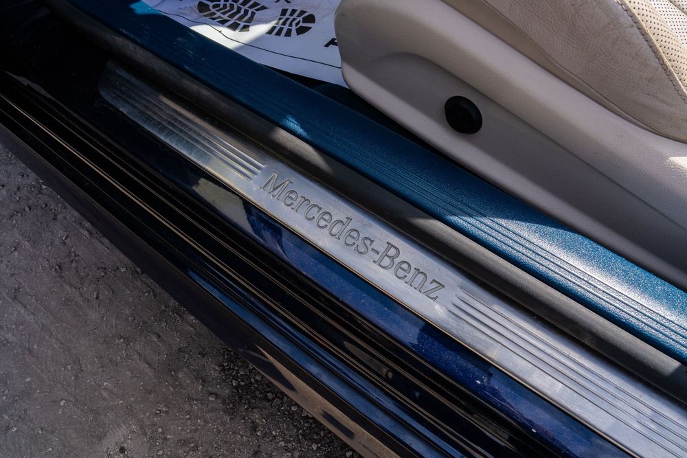 Close-up view of a Mercedes-Benz door sill plate with illuminated branding detail.