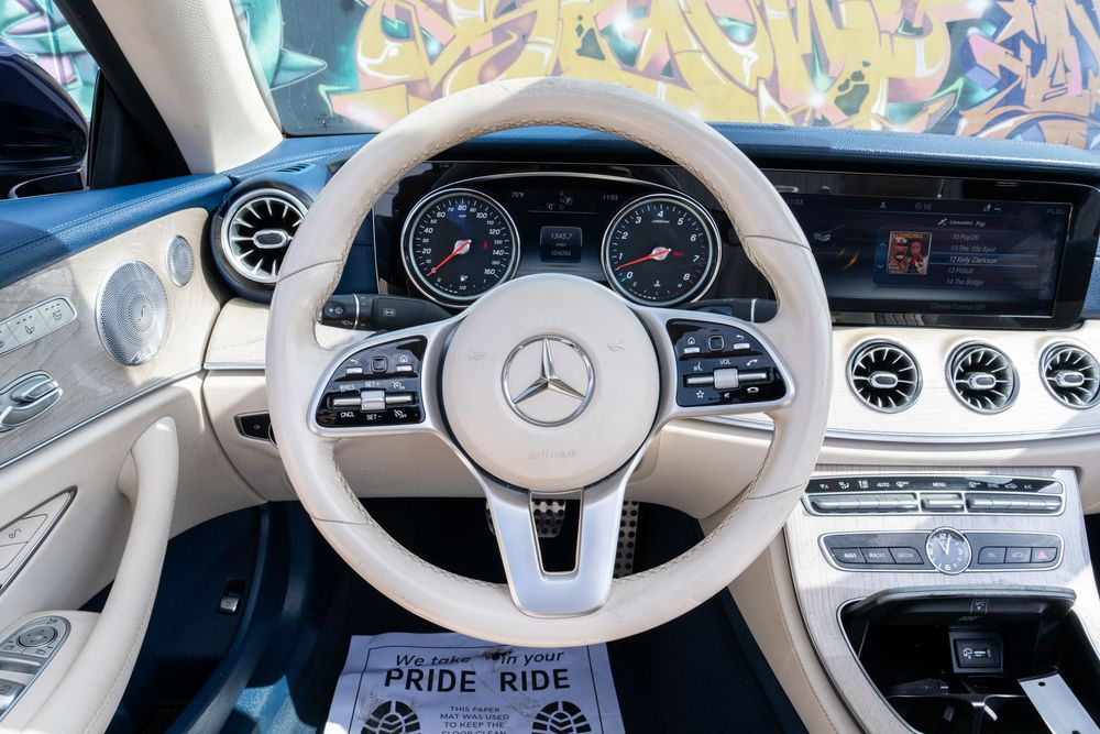 Modern Mercedes-Benz interior featuring white leather steering wheel and digital dashboard displays.