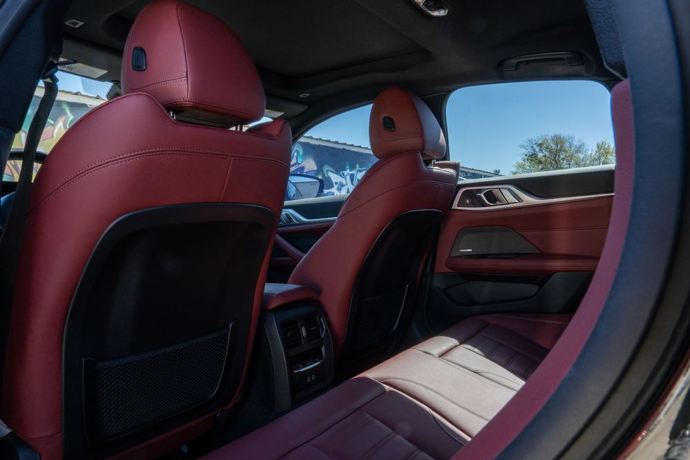Luxurious red leather interior of a BMW M vehicle showing sport seats and door panels.