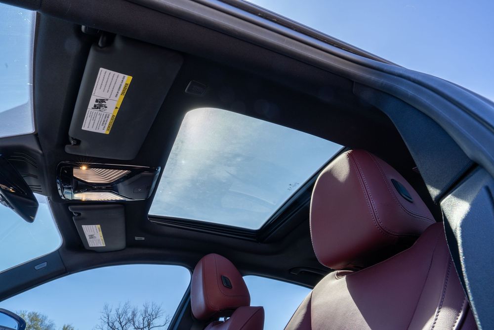 Interior view of luxury car showing burgundy leather seats and panoramic glass roof.