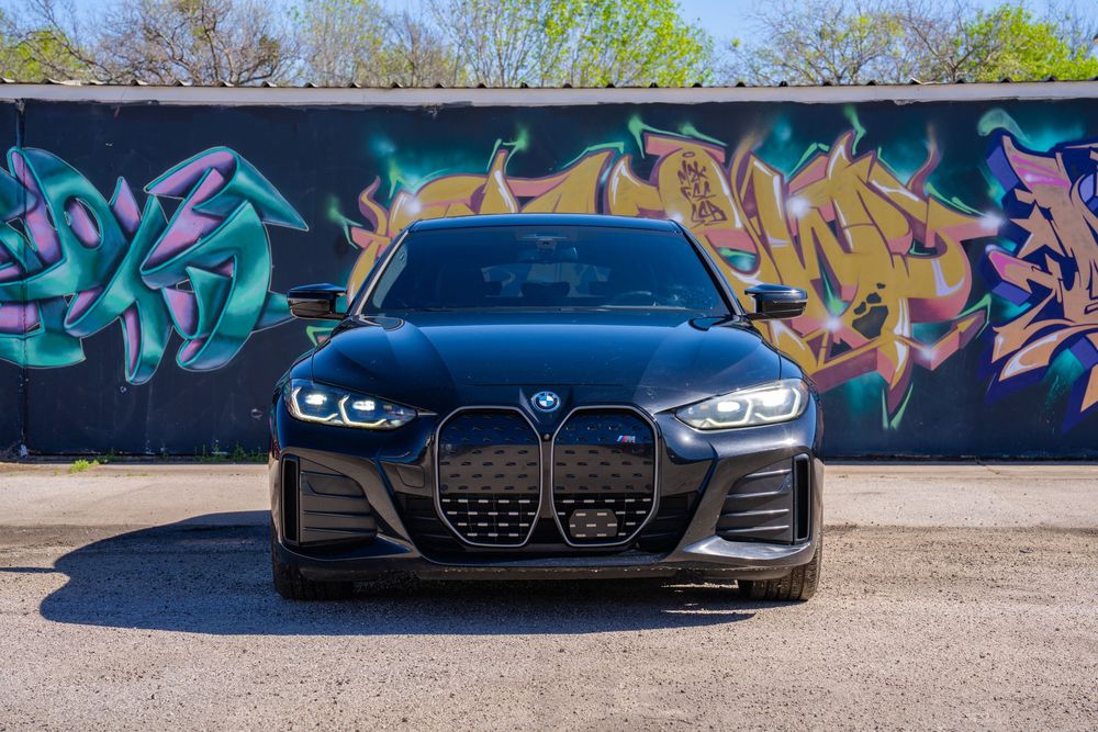 BMW 4 Series cars lined up in front of colorful graffiti wall showing their distinctive front grille designs.