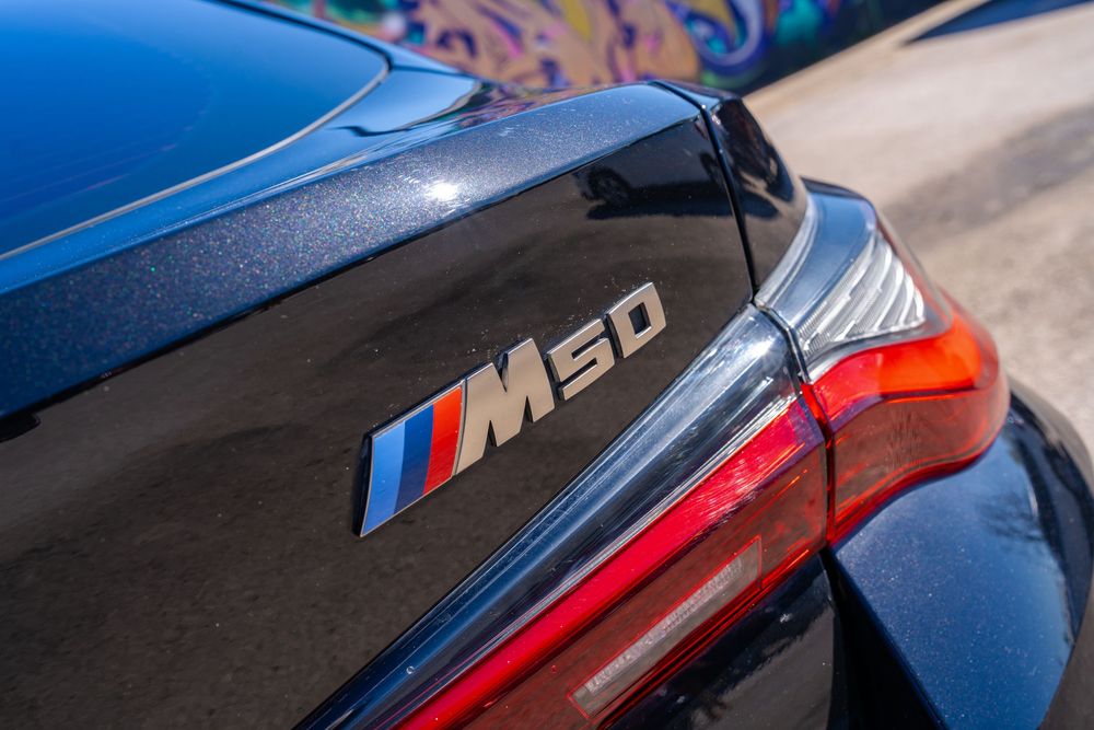 Close-up view of a BMW M5 CS badge in blue and red colors on a dark surface.