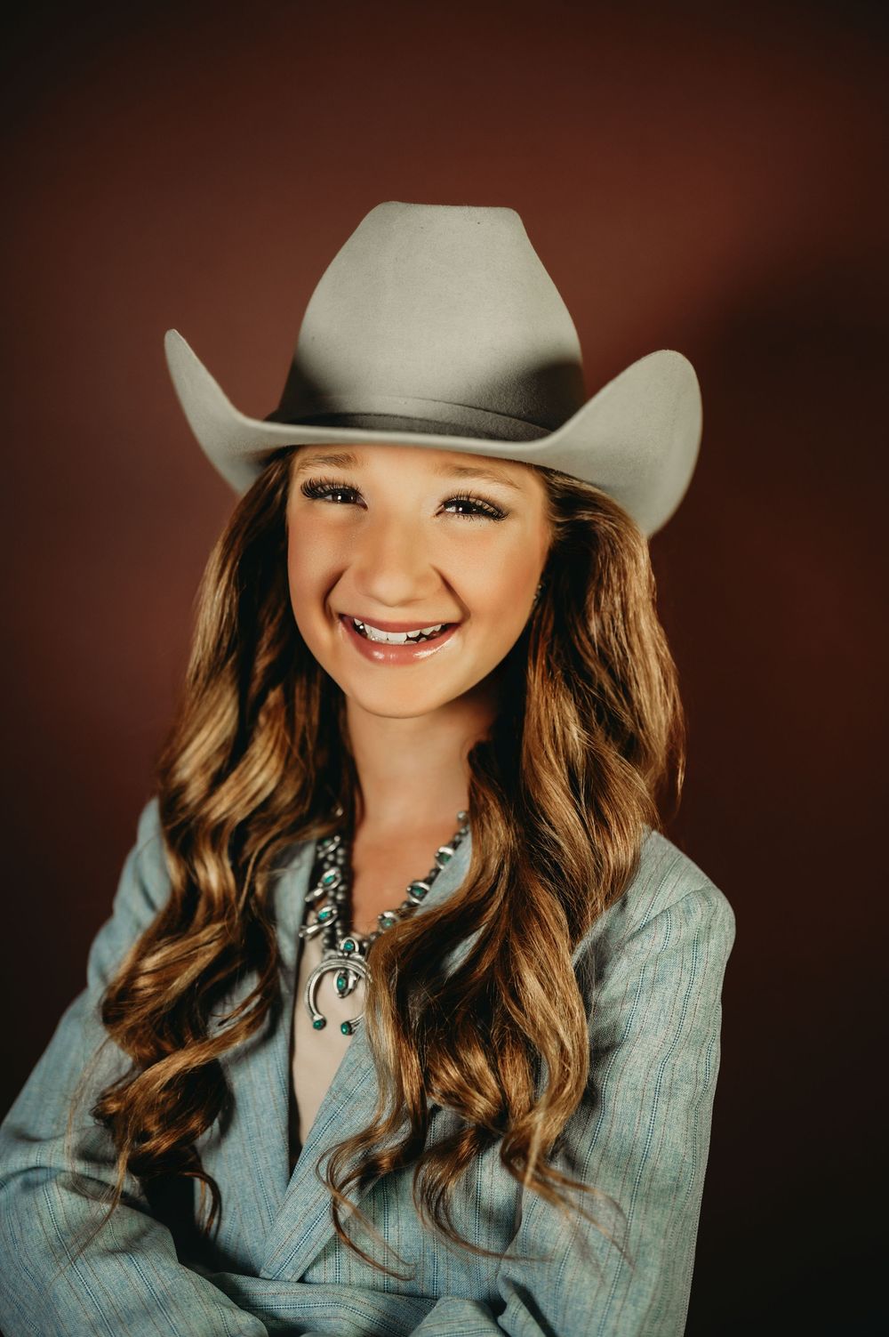 Country western themed portrait with turquoise jewelry and light wash denim jacket.