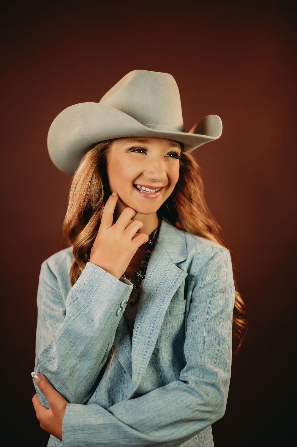 Casual western portrait featuring denim jacket and cowboy hat with warm lighting.