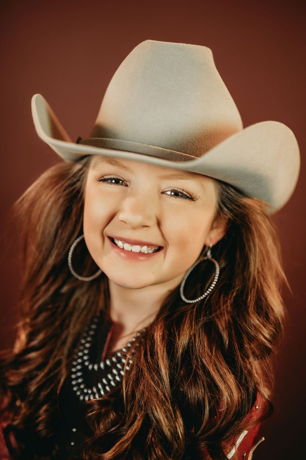 Western style portrait with silver jewelry, cowboy hat and flowing hair.