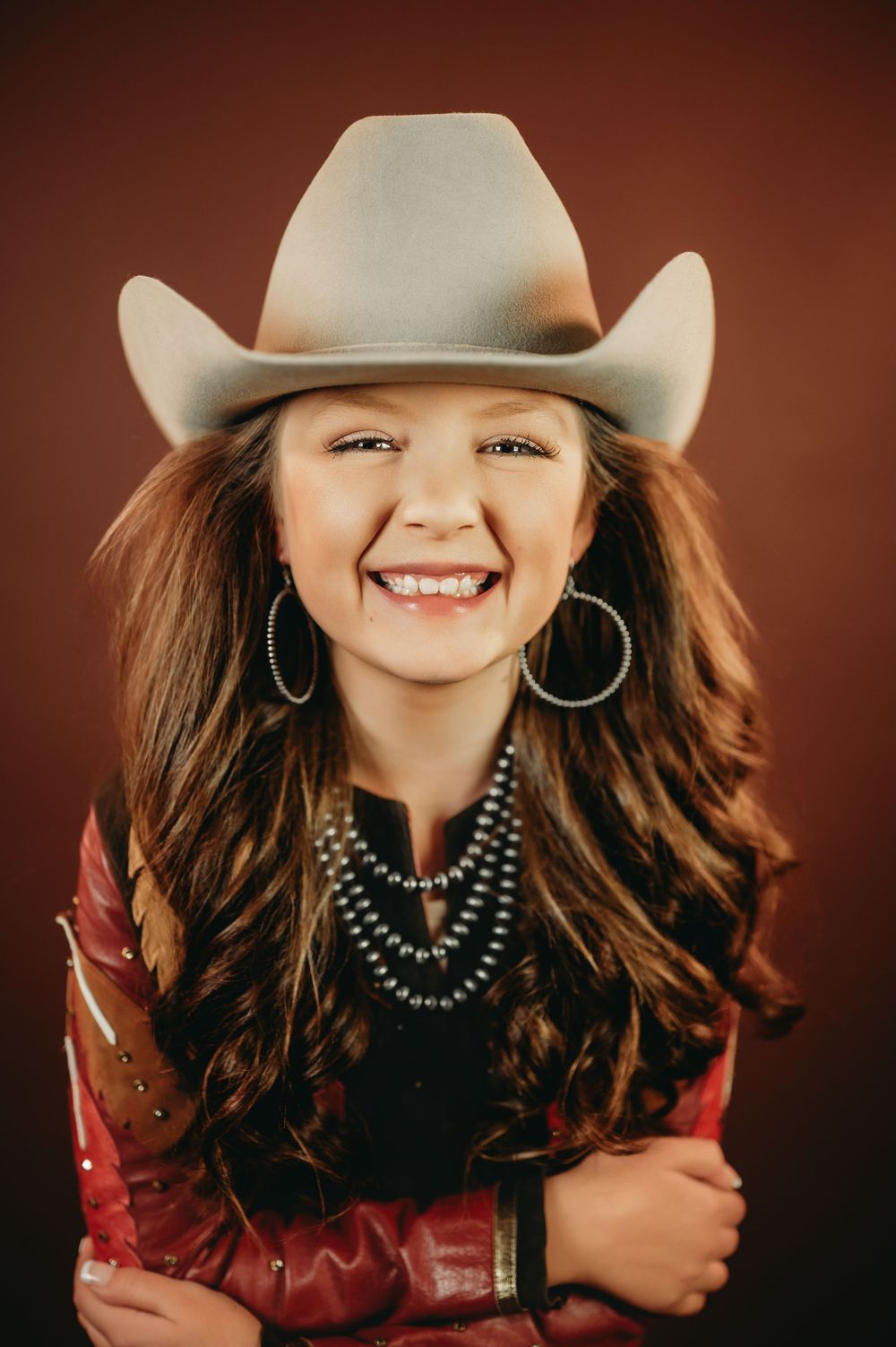 Western themed portrait with layered necklaces and red leather jacket.