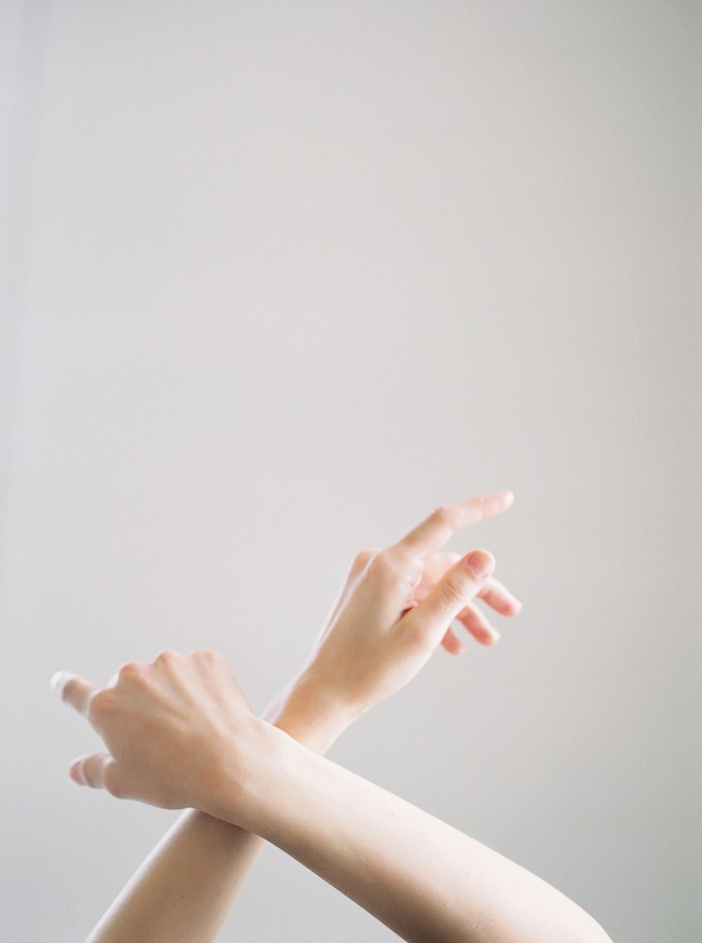 Series of graceful hand gestures photographed against a soft white background in minimalist style.