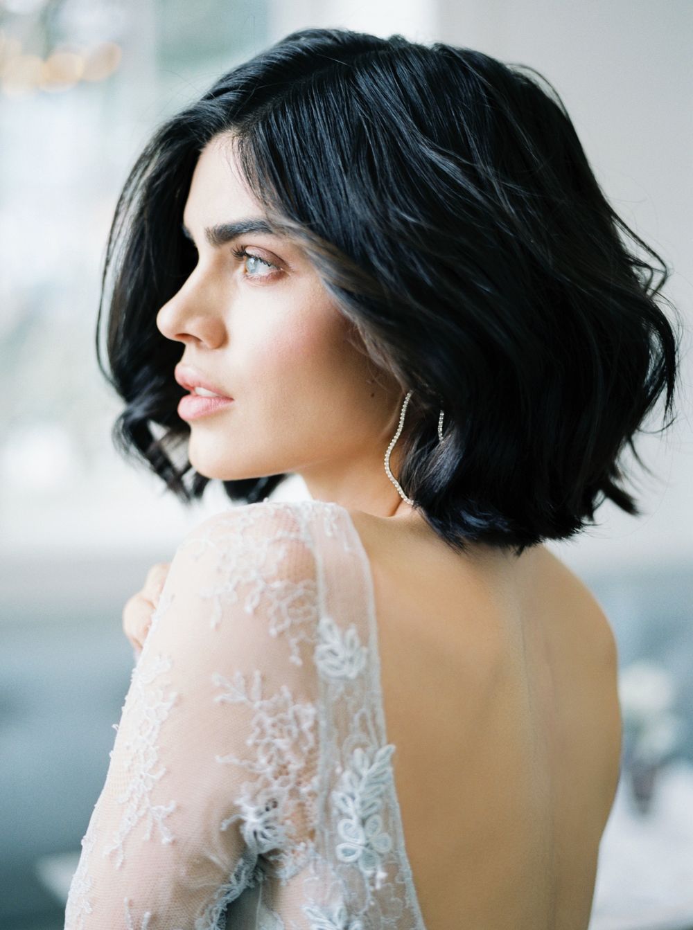 Side profile portrait featuring short black hair and elegant white lace bridal gown.