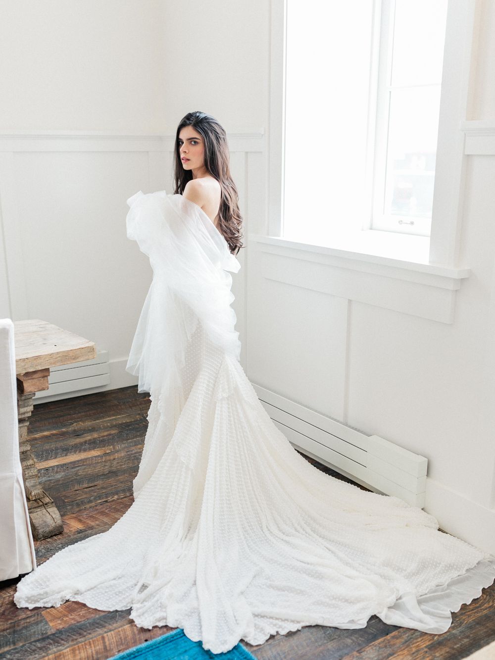 Ethereal white wedding gown with flowing train captured in sequence against rustic wooden floors and white walls.