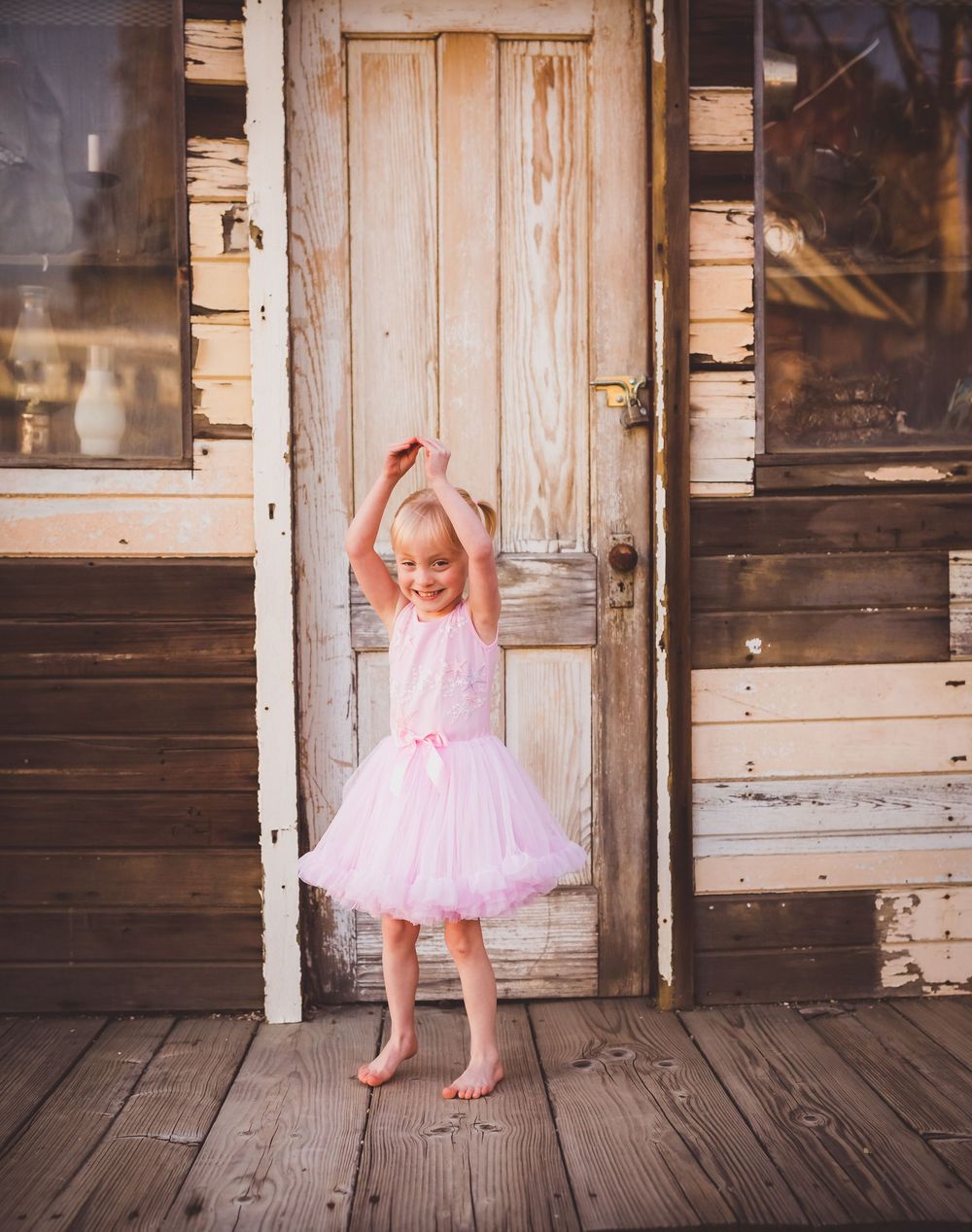 A sequence of photos showing a small child in a pink tutu dress dancing and twirling on a rustic wooden porch.