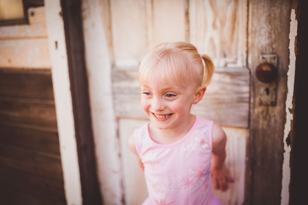 A pink tutu dress twirls against a rustic wooden porch backdrop in a series of candid moments.