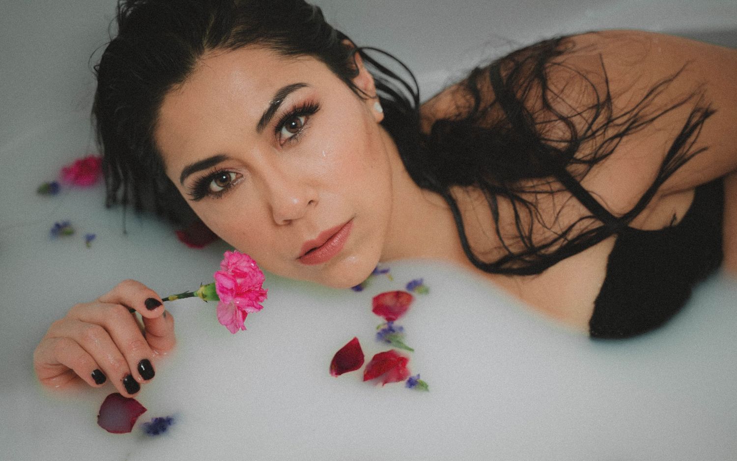 A collage of beauty portraits showing dark hair with pink floral accents and rose petals in a dreamy style.