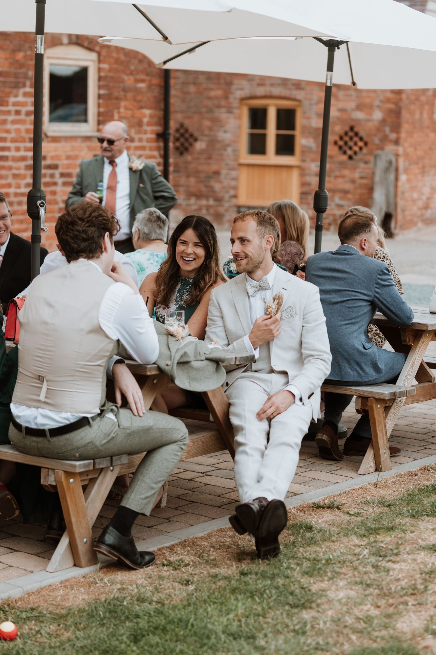 Wedding guests celebrate during an outdoor reception with joyful expressions and interactions at Moat Hall Barns