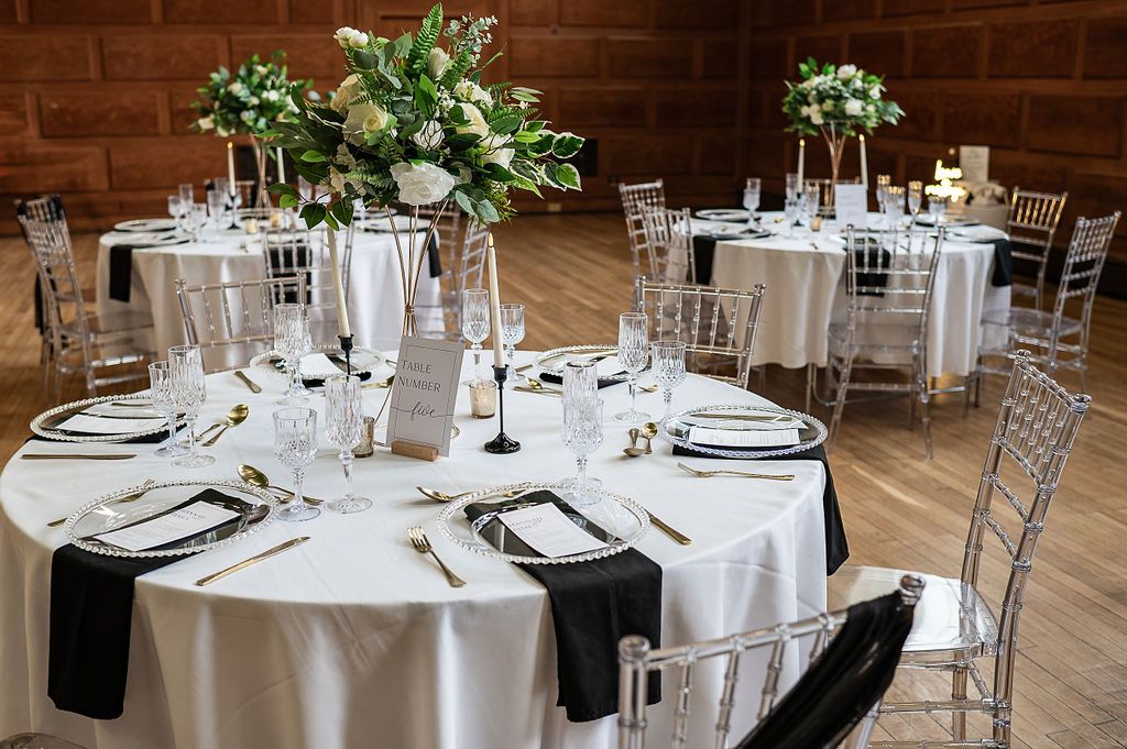 Eco wedding reception table layout in glamourous black, white and gold style.  The round tables have floral centrepieces