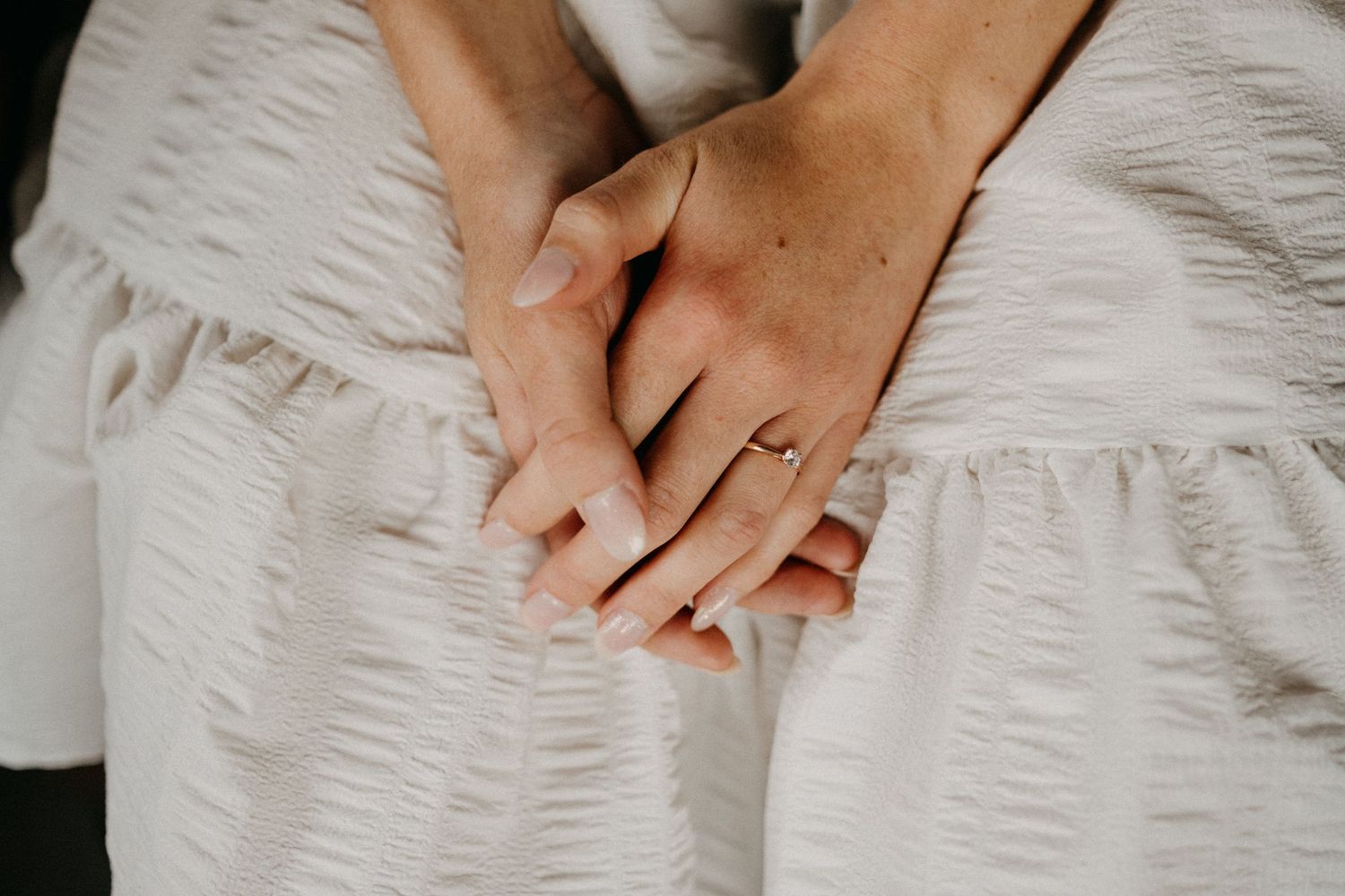 Close-up shot of hands resting on white textured fabric with delicate details.