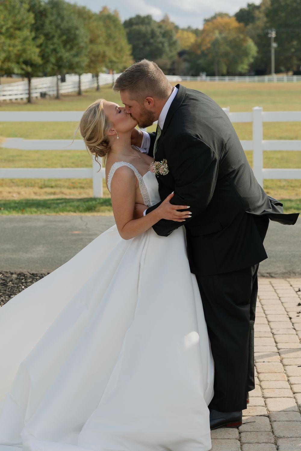 A romantic first look moment between newlyweds on a stone patio with white fencing in the background.