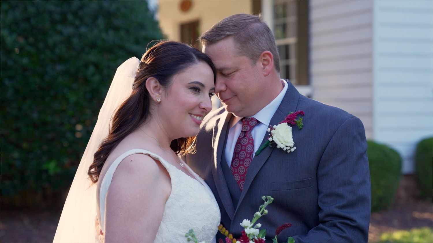 A bride and groom share an intimate moment during their wedding ceremony, with the bride holding a floral bouquet.
