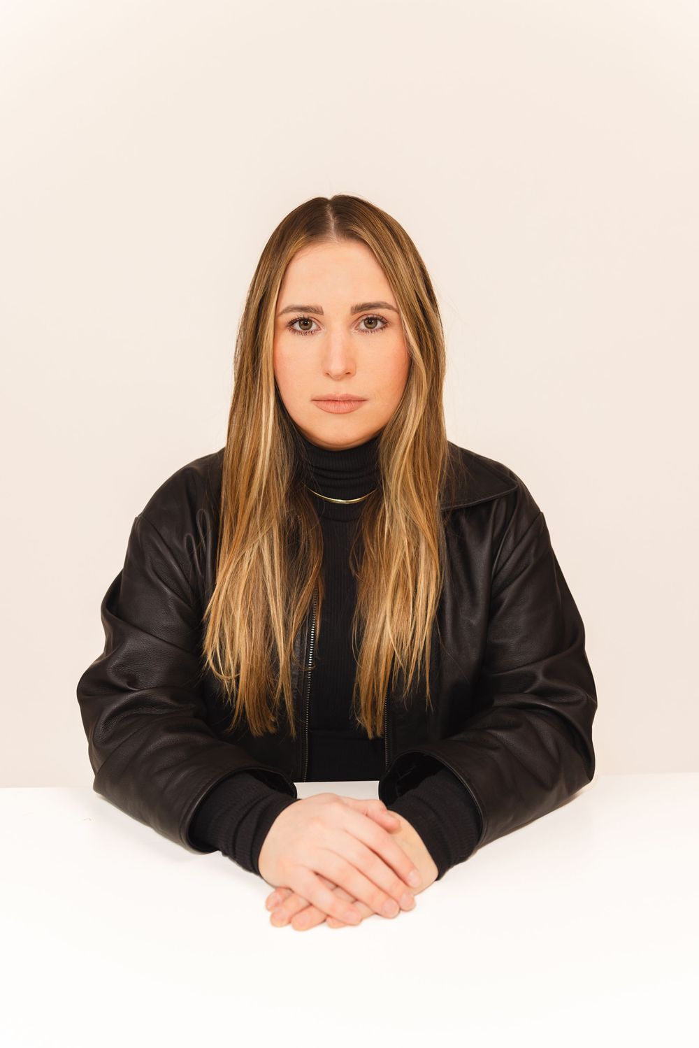 Person with long blonde hair wearing black clothing poses in three similar headshots against white background.