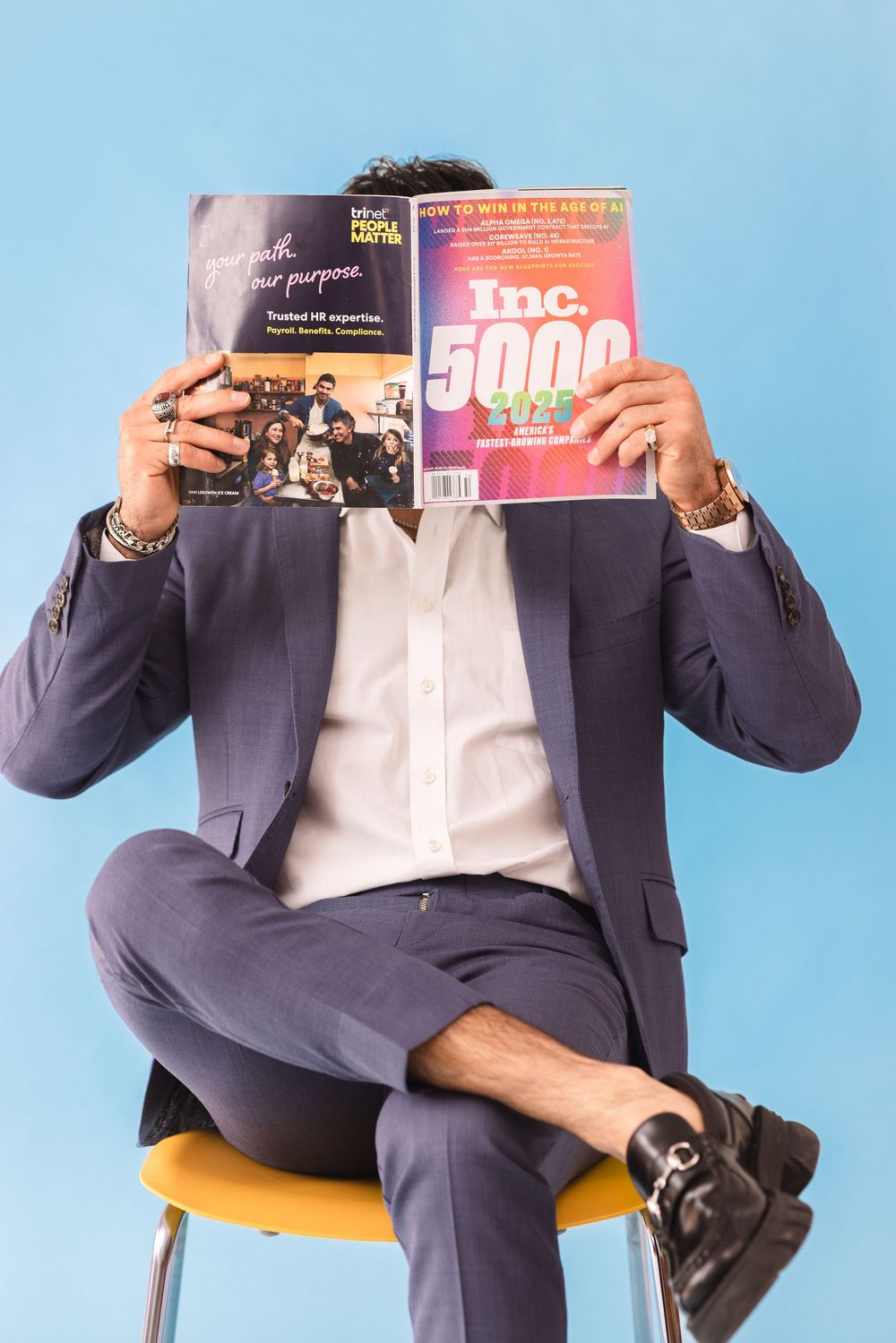 Professional in navy suit sits on yellow chair reading business magazine in sequence of four progressive shots.