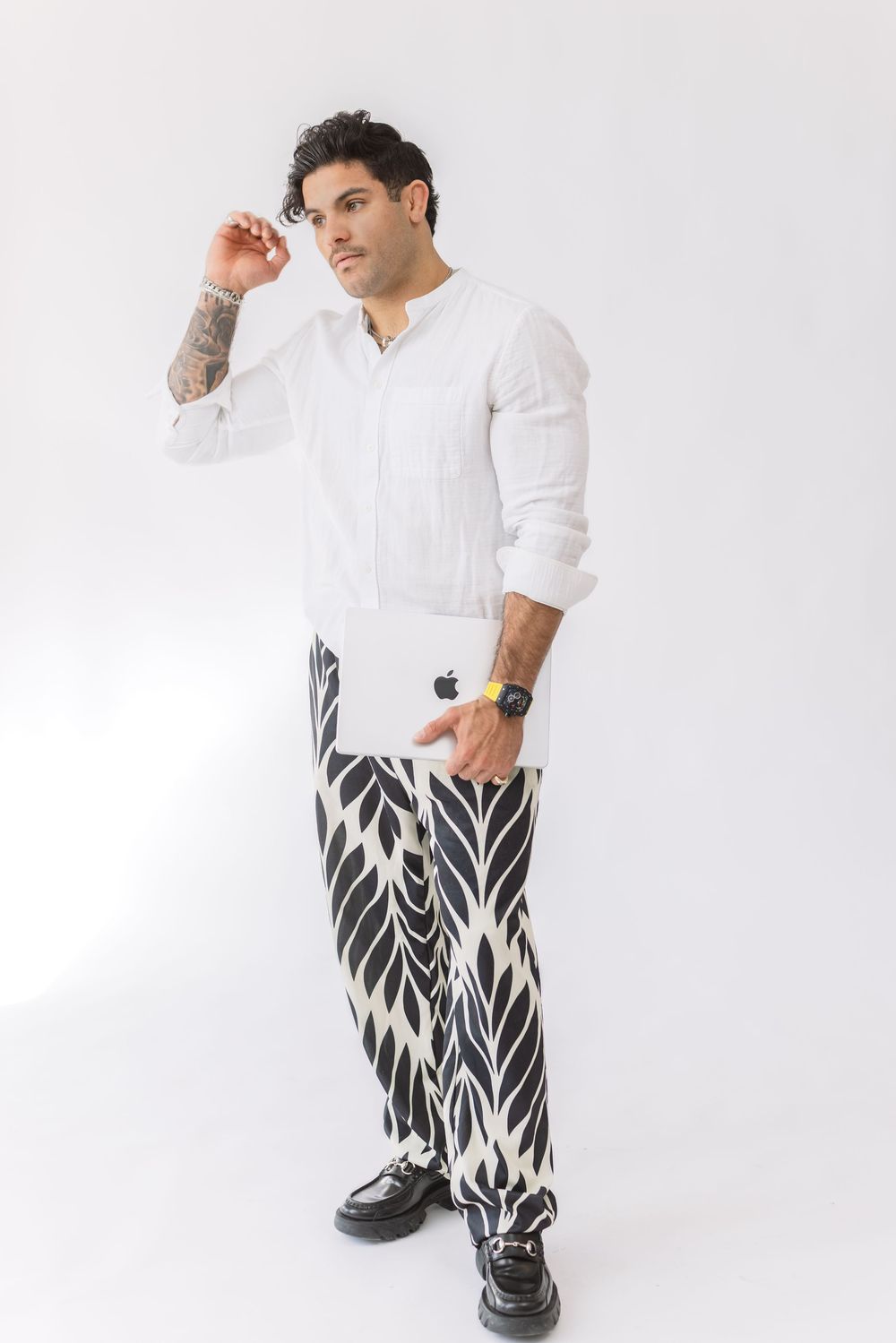Model in white t-shirt and black and white patterned pants poses against white background in three different angles.
