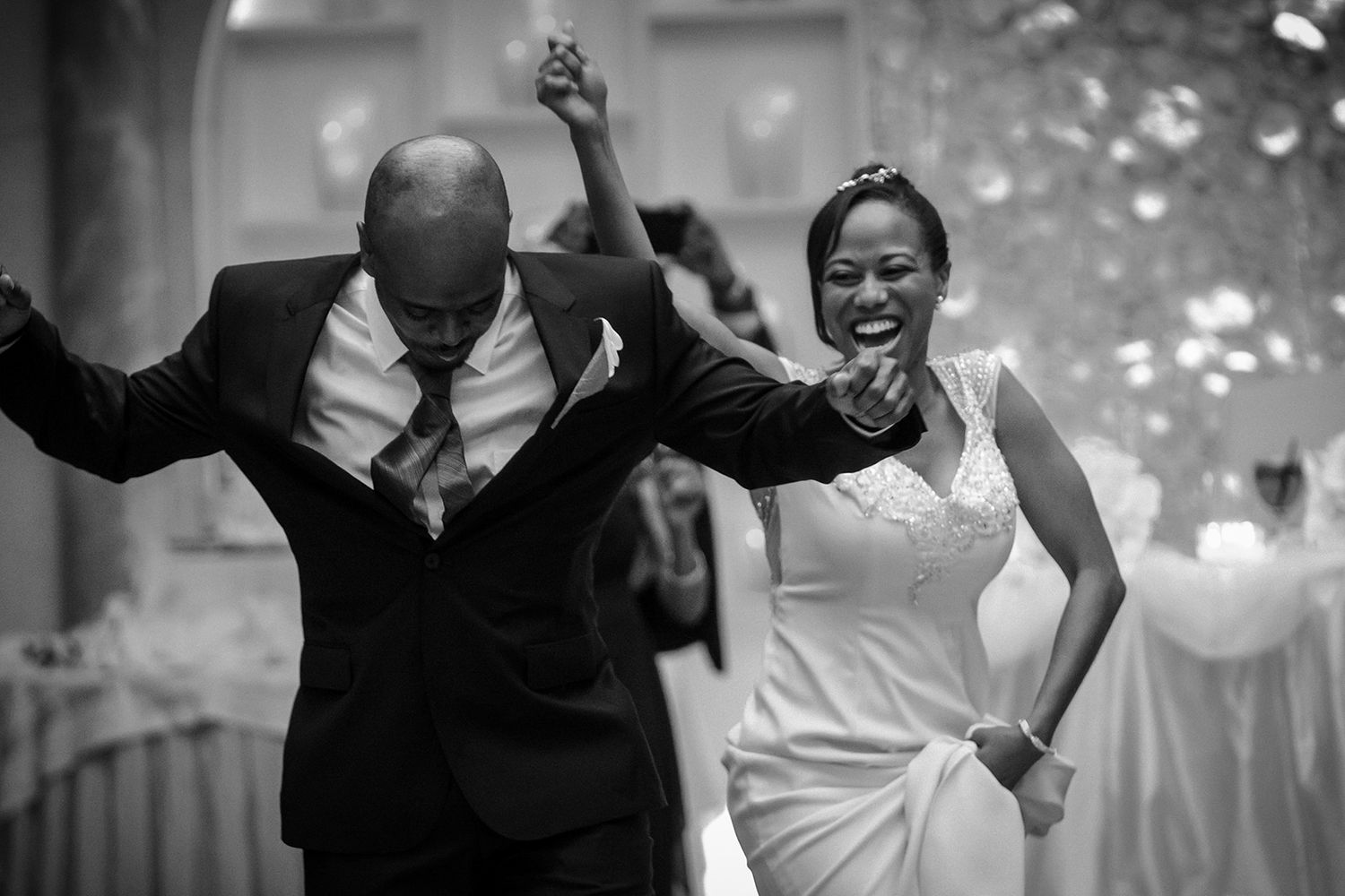 Black and white photo of wedding guests dancing and celebrating at a reception.