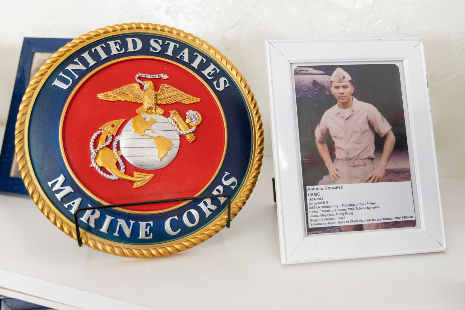 close up detail shot of a marine crops emblem along with a photo framed of a marine in their uniform.