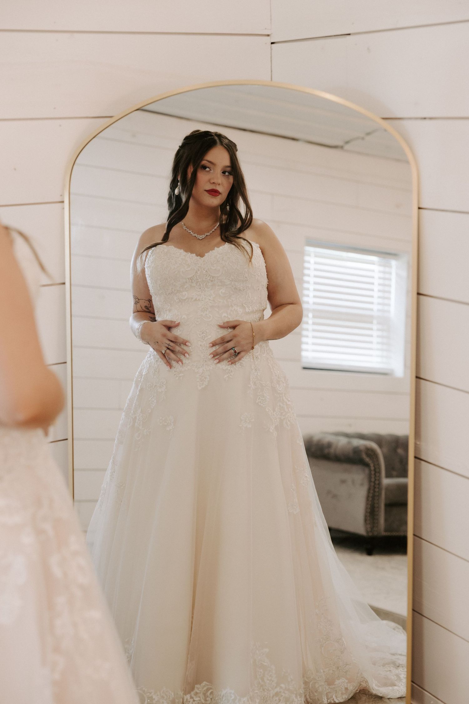A series of bridal photos showing details of a white lace wedding dress with off-shoulder design in a light-filled room.
