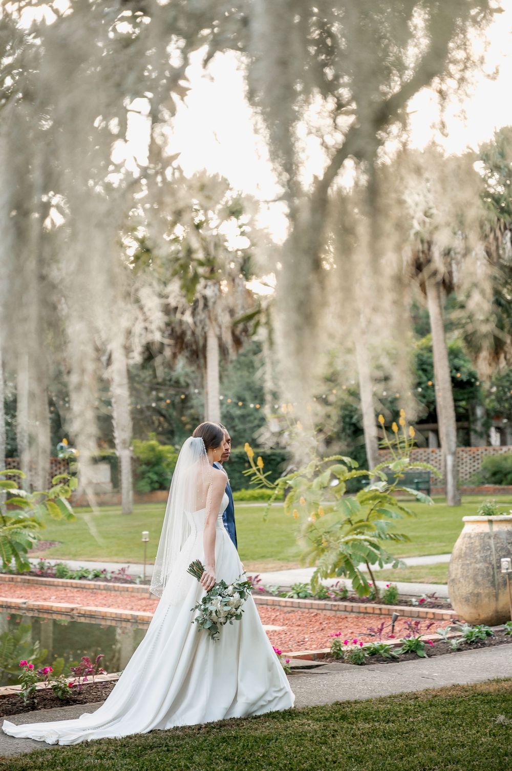 Elegant wedding portraits captured in a dreamy garden setting with Spanish moss hanging from trees.