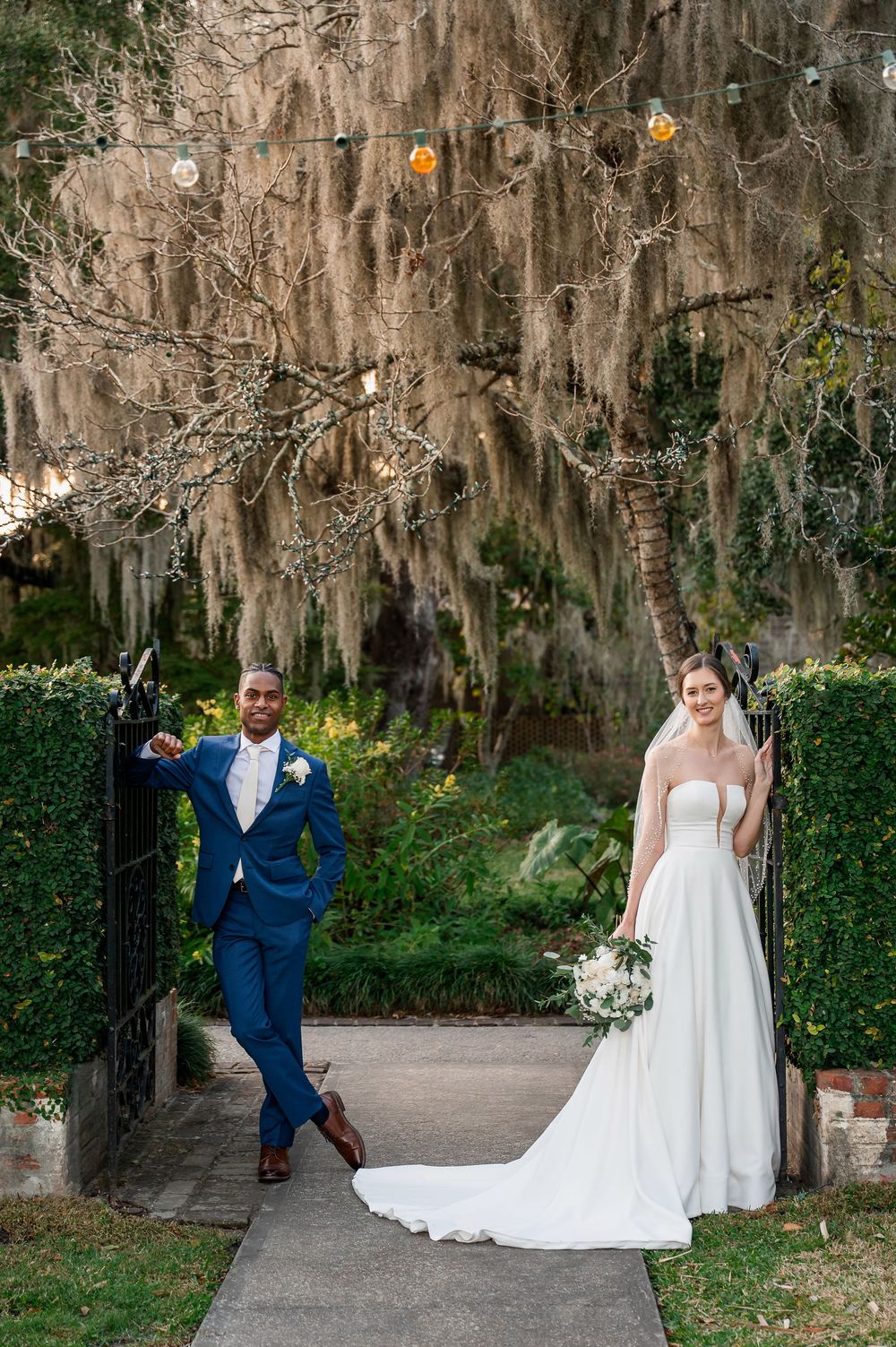 Wedding photography session along a brick pathway surrounded by moss-covered trees.