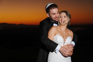 A romantic wedding couple embraces during sunset while dancing together on their special day.