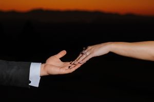 Two hands reach toward each other against a dark background in a dramatic recreation of Michelangelo's Creation of Adam.